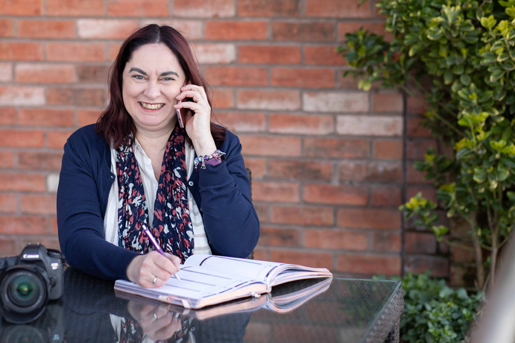 Woman on phone with camera and diary on table