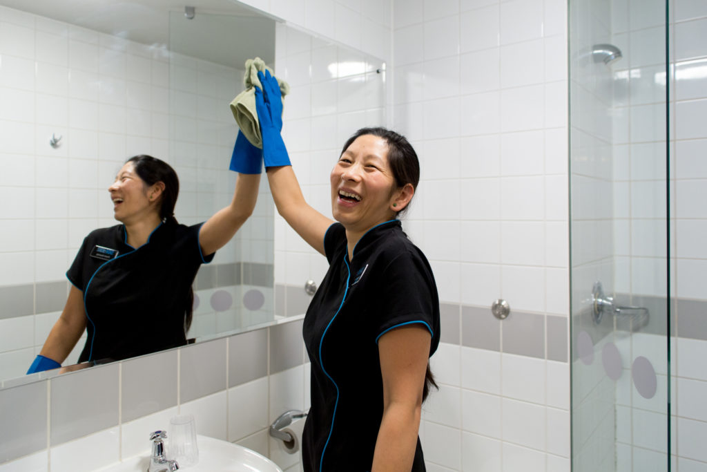 Happy woman cleaning a mirror