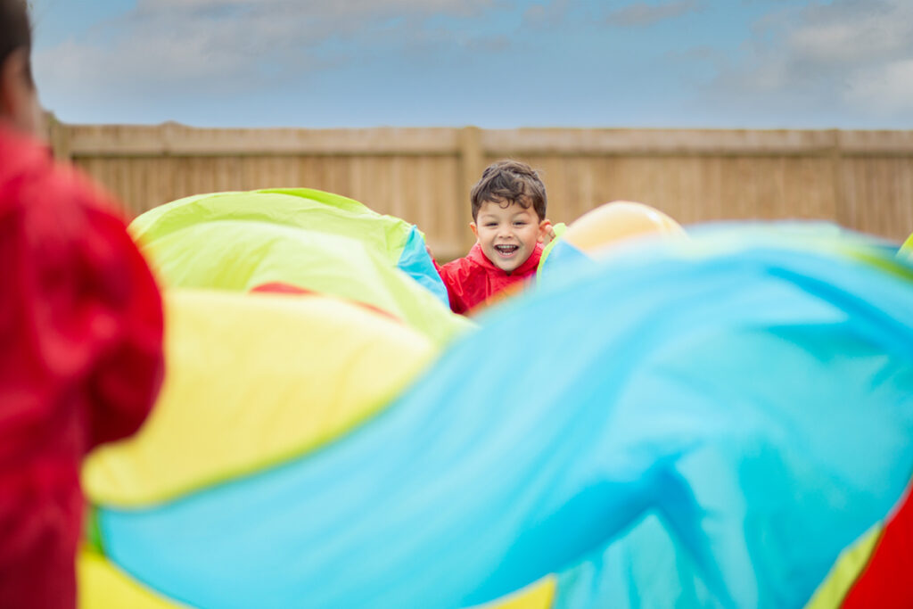 child playing with colourful parachute